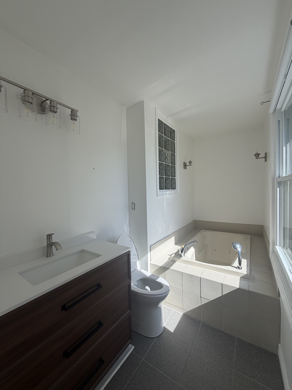 Bathroom with jetted tub, tiled platform and glass-block window before conversion