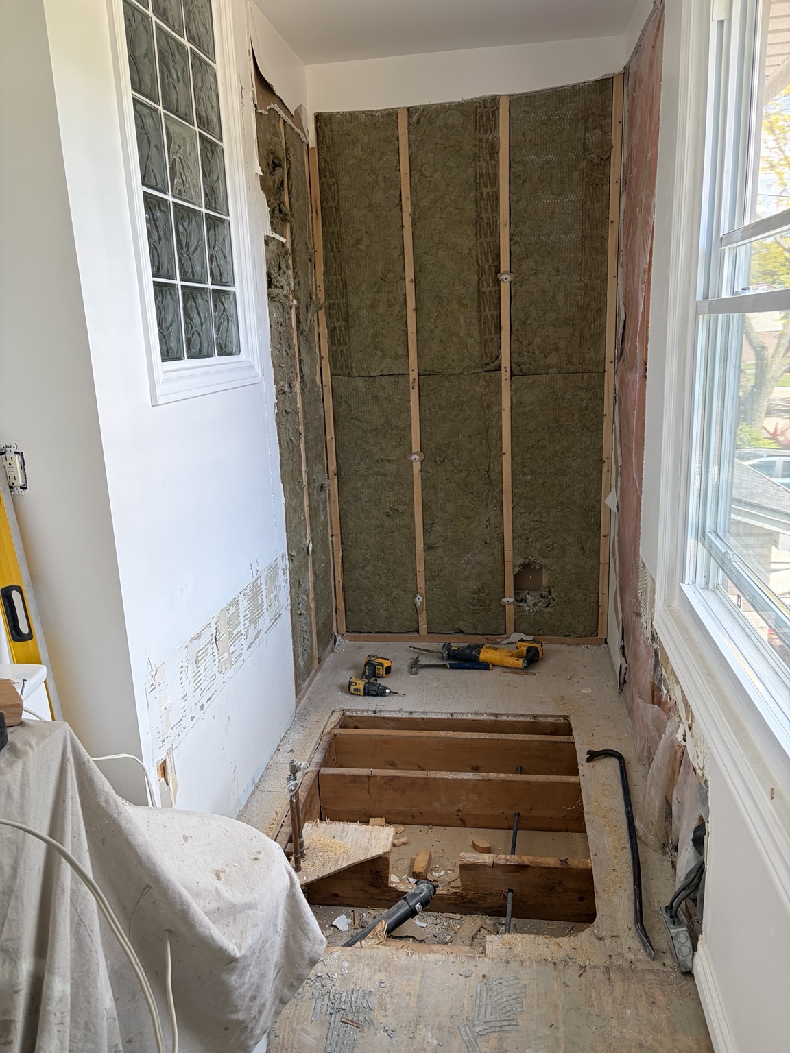 Tub removed with wall insulation and floor framing exposed