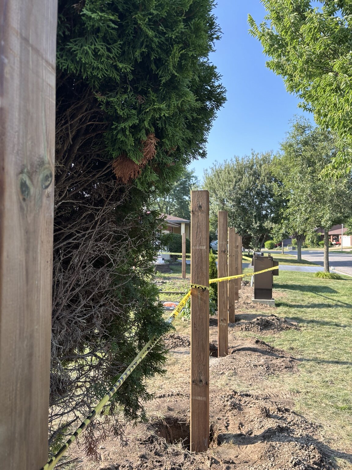 New wood fence posts aligned through a London front yard during installation