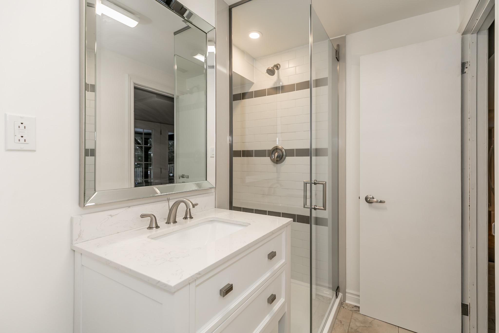 Hilltop basement bathroom after renovation with a white vanity and glass shower
