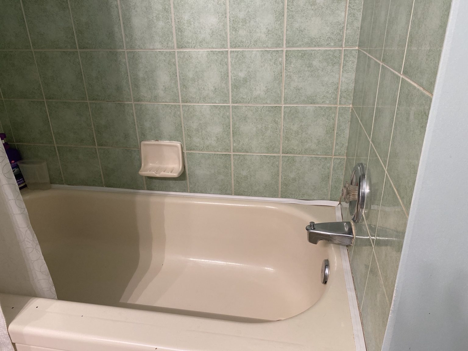 Hilltop upstairs bathroom before renovation with green tile around the tub