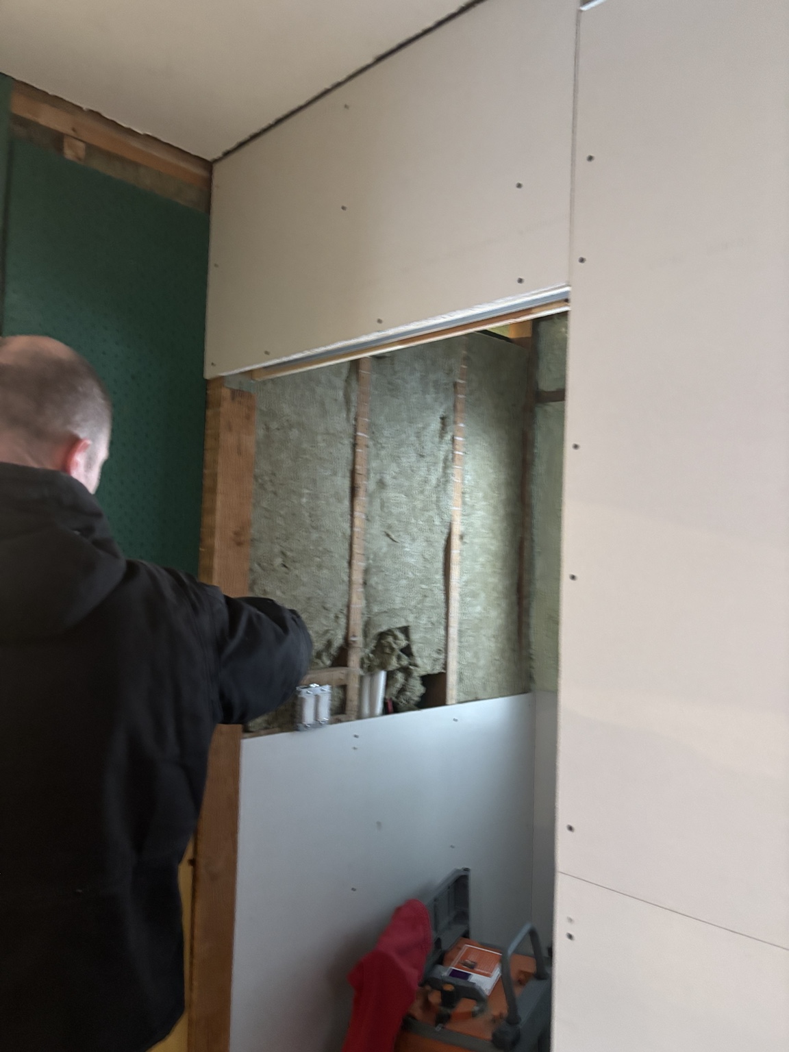 Drywall being installed over insulated wall cavities