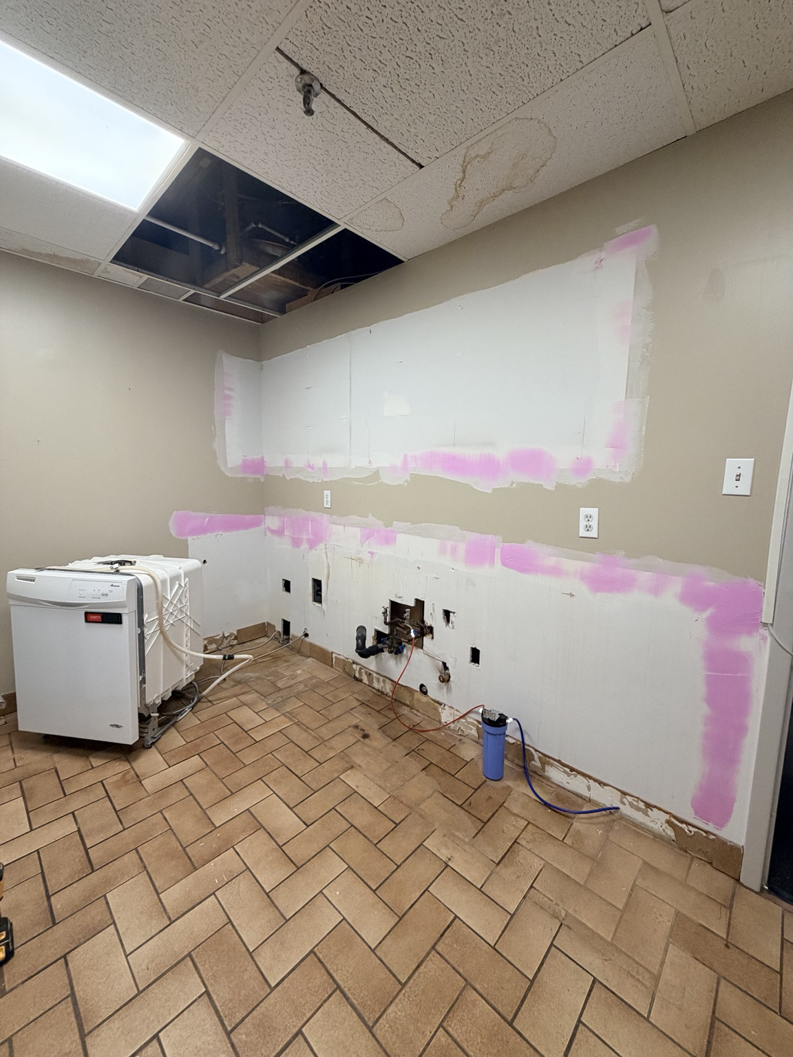 Office kitchen wall opened for plumbing and repair access