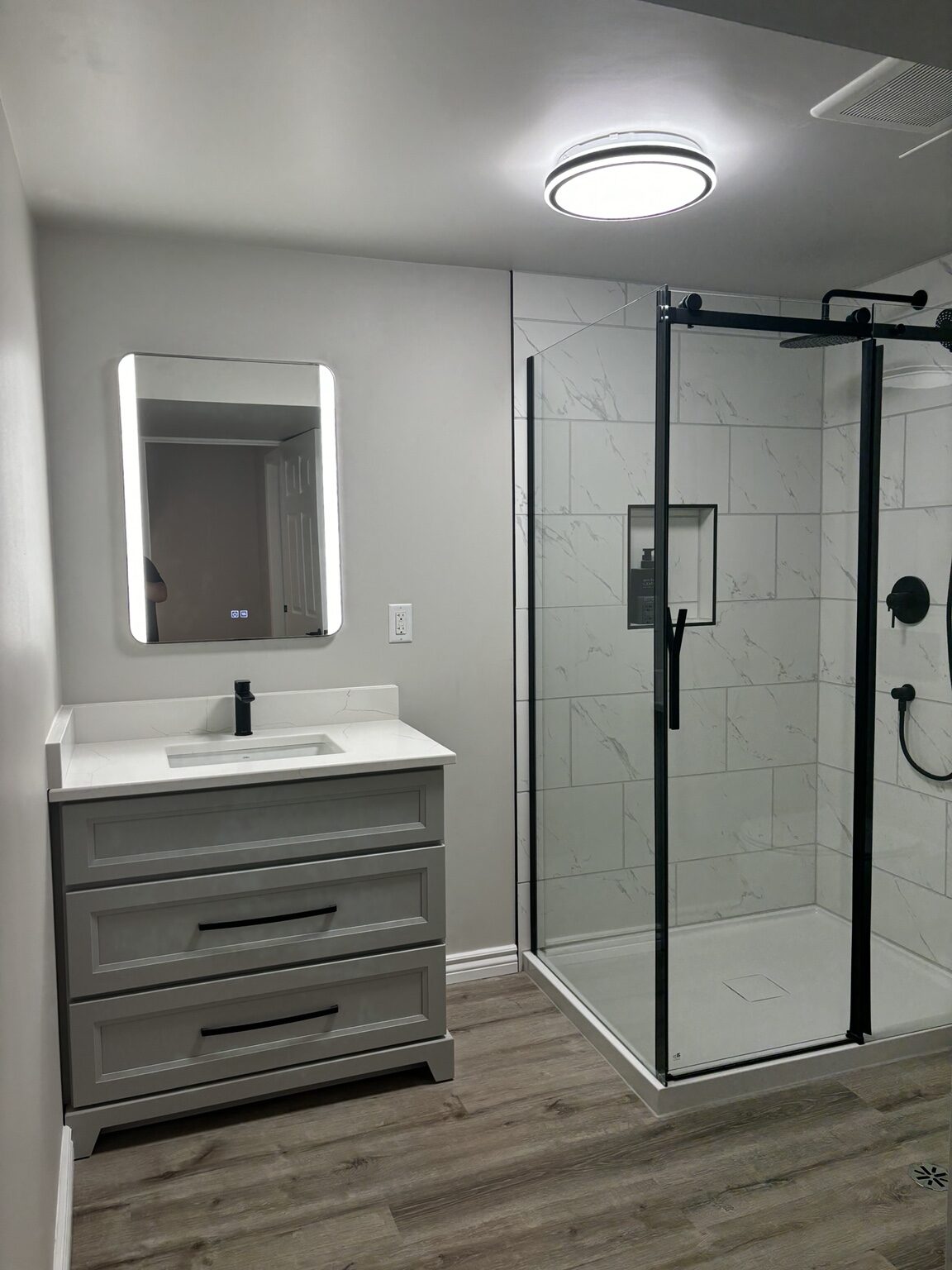 Completed Melrose-area bathroom with tiled shower, wall-hung toilet and illuminated mirror