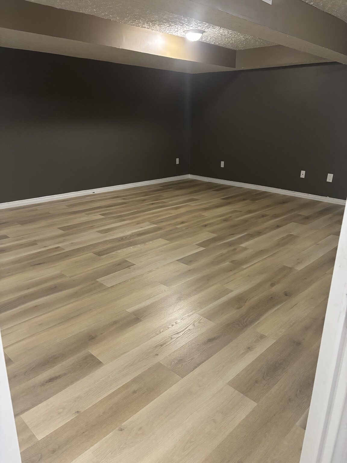 Same Pond Mills lower-level room with completed light plank flooring and baseboards