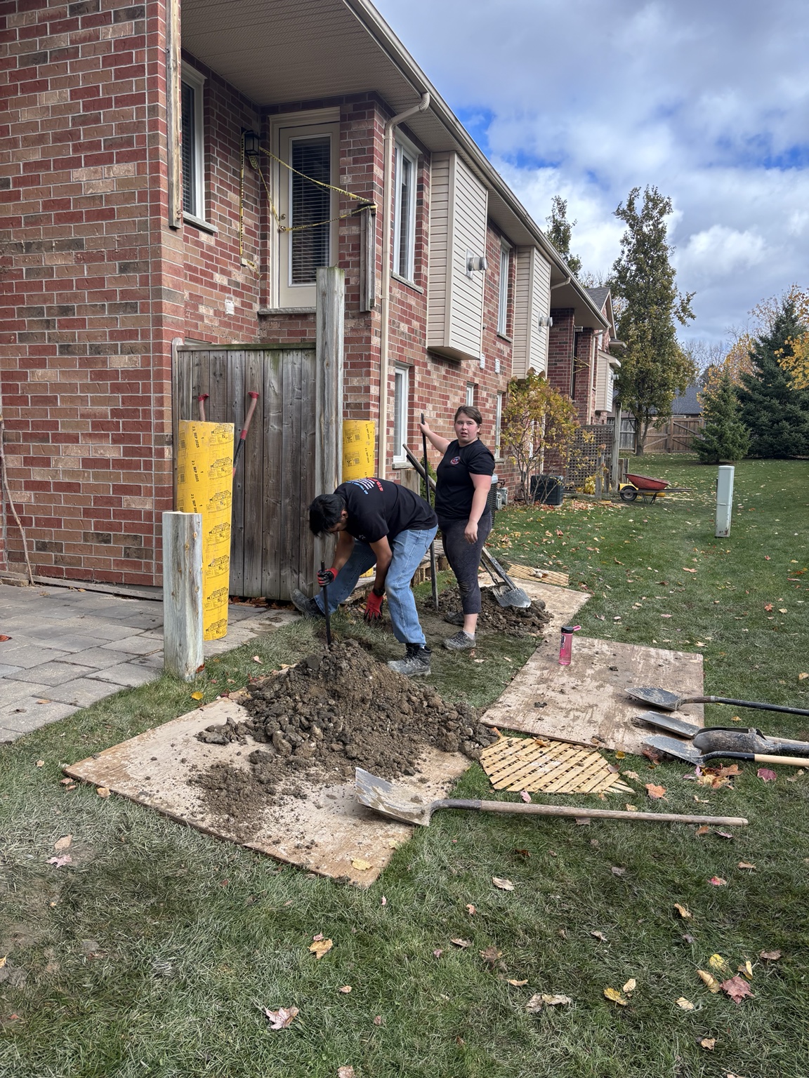 Post hole being dug by hand beside a residential property