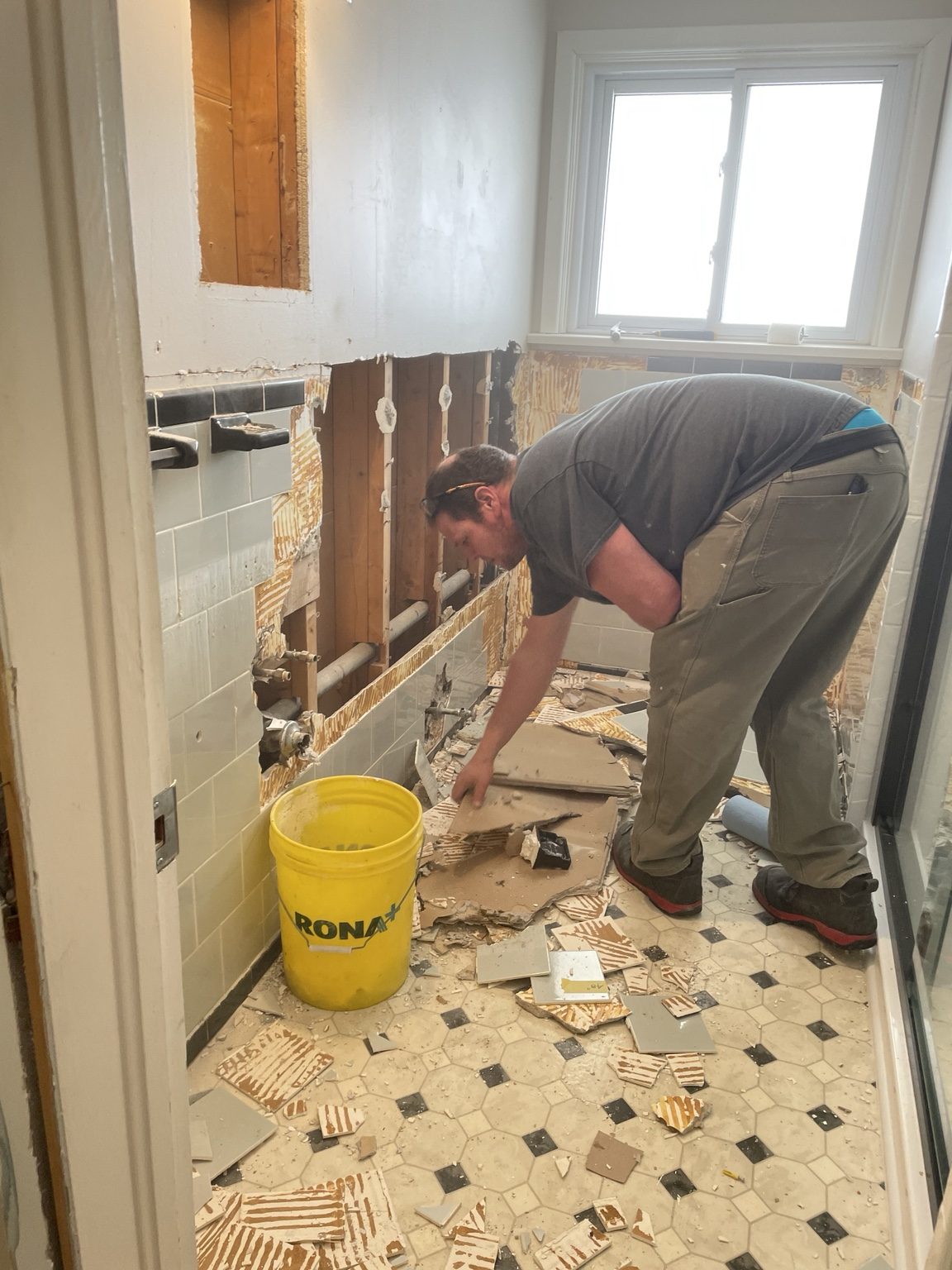 Wall tile being removed in the frosted-window bathroom