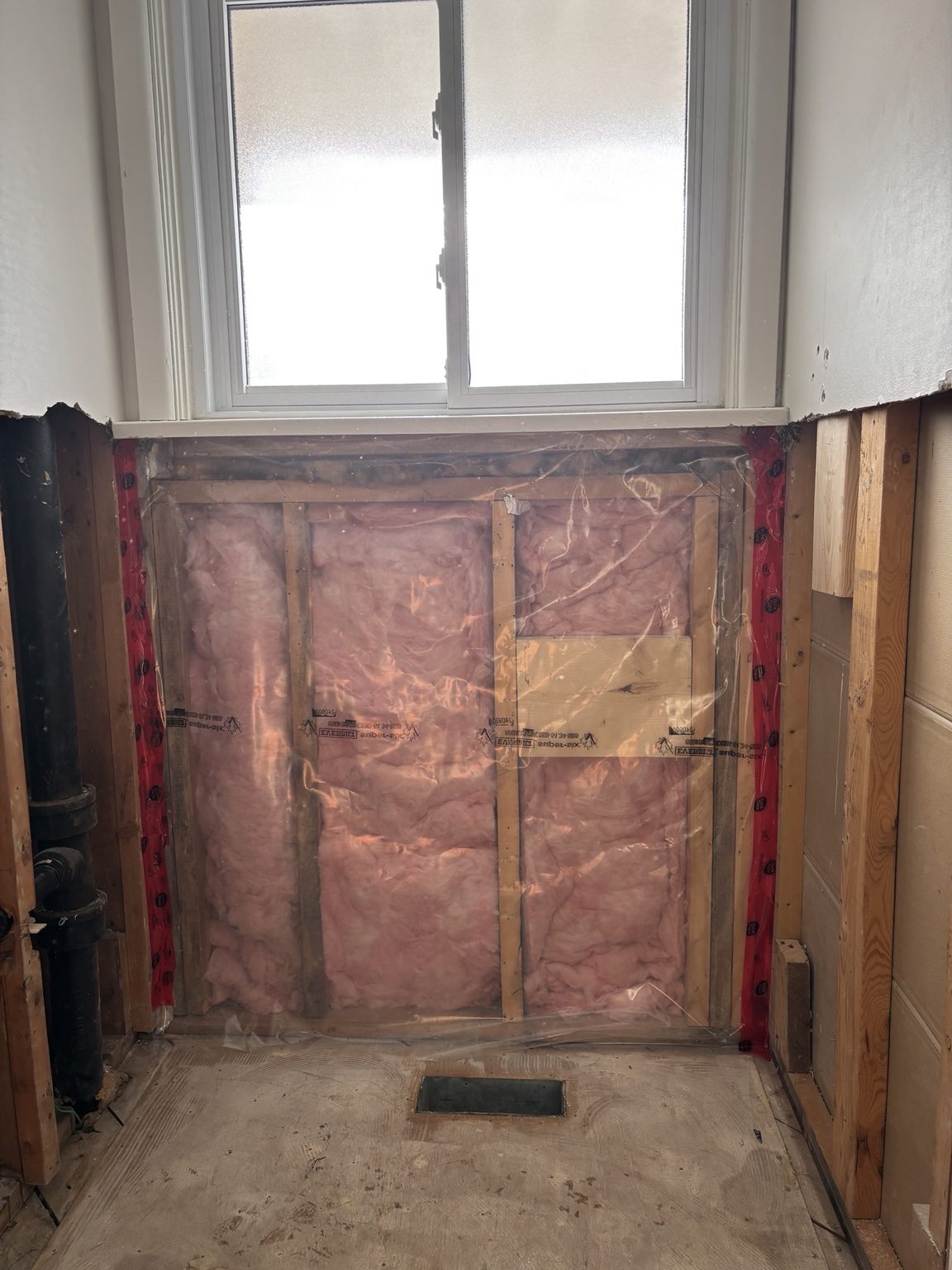 Exterior wall opened to insulation beneath the bathroom window
