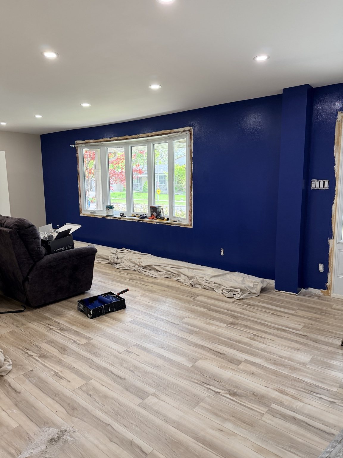 Completed Westmount living-space phase with plank flooring, pot lights and a deep-blue feature wall